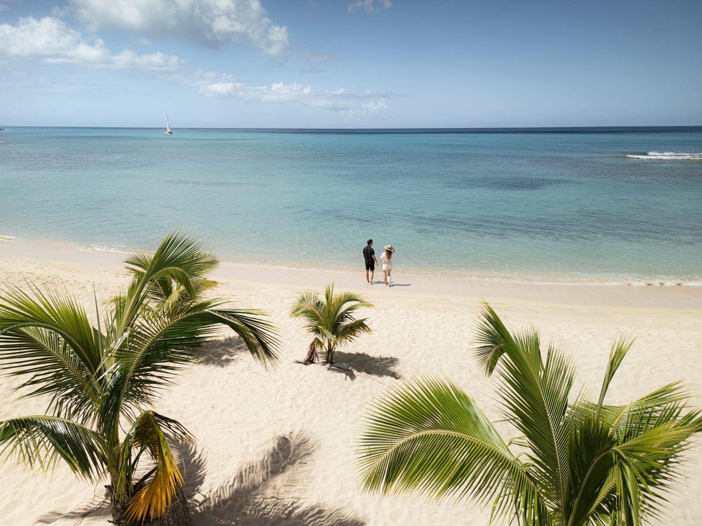 Paar am karibischen Palmenstrand mit türkisblauem Meer und weißem Sand