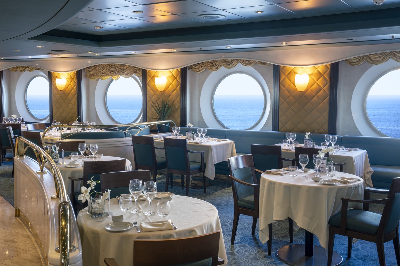 Restaurant an Bord mit großen Bullaugen und festlich eingedeckten Tischen