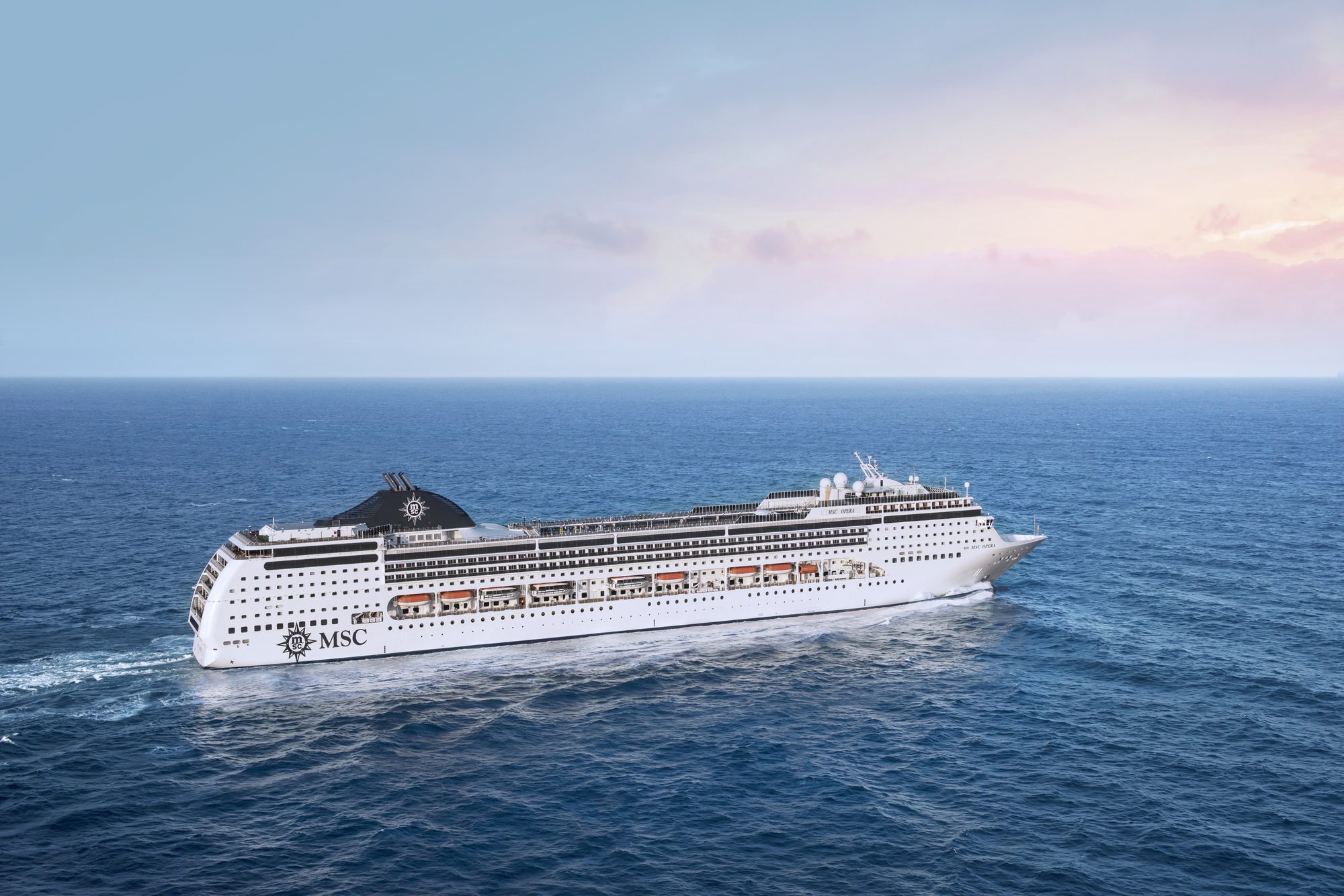 MSC Opera in Fahrt auf offener See im Abendlicht mit pastellrosa Himmel