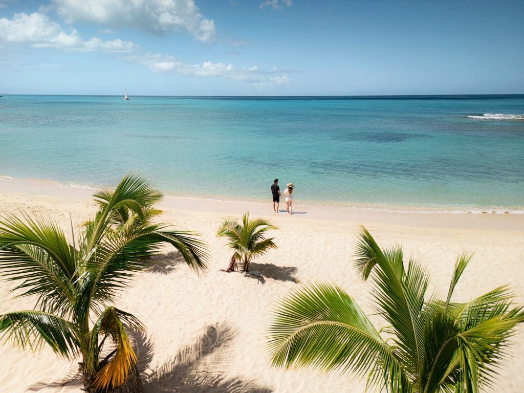 Paar am karibischen Palmenstrand mit türkisblauem Meer und weißem Sand