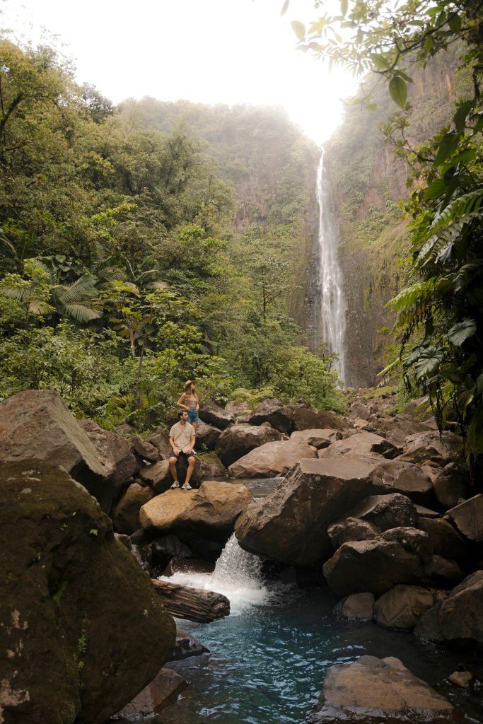 Hoher Wasserfall im Regenwald mit Felsen und türkisblauem Wasserbecken