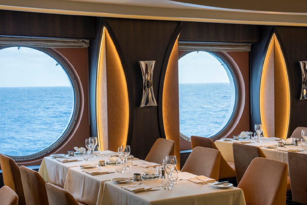 Restaurant an Bord mit runden Panoramafenstern und festlich eingedeckten Tischen
