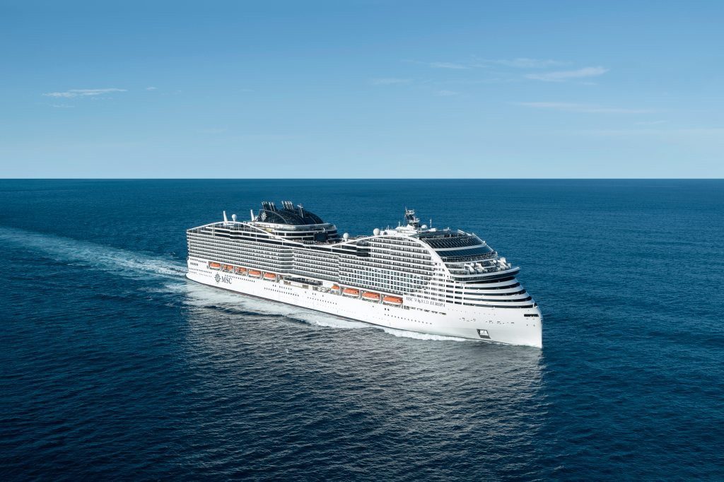 MSC World Europa in Fahrt auf tiefblauem Meer unter klarem Himmel, Luftaufnahme schräg von vorne